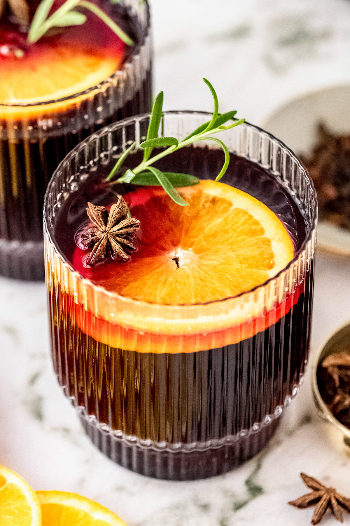 Mulled wine garnished with an orange slice, star anise, and rosemary.