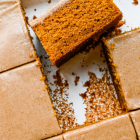 A slice of pumpkin sheet cake in a baking pan turned on it's side to show the pumpkin cake.