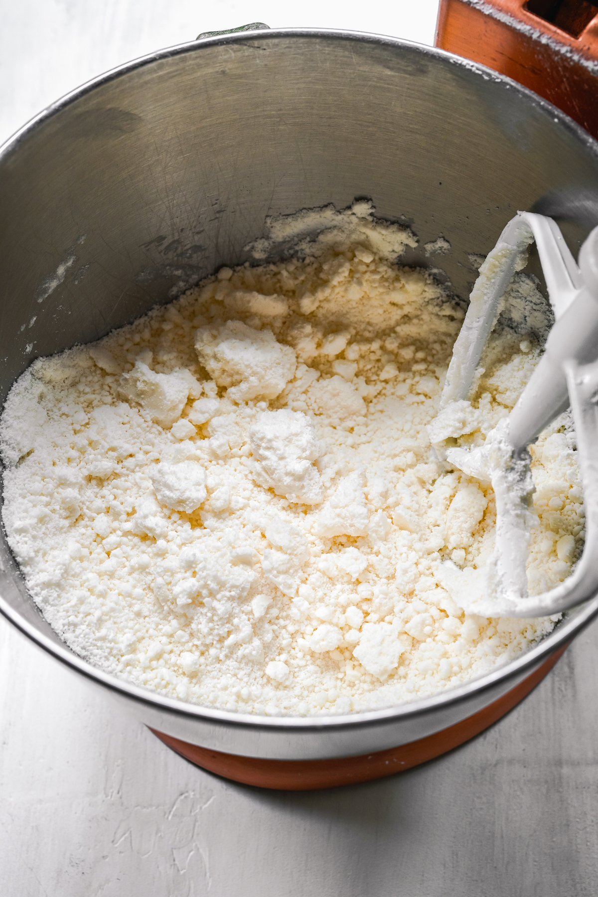 Powdered sugar and butter being mixed in a stand mixer.