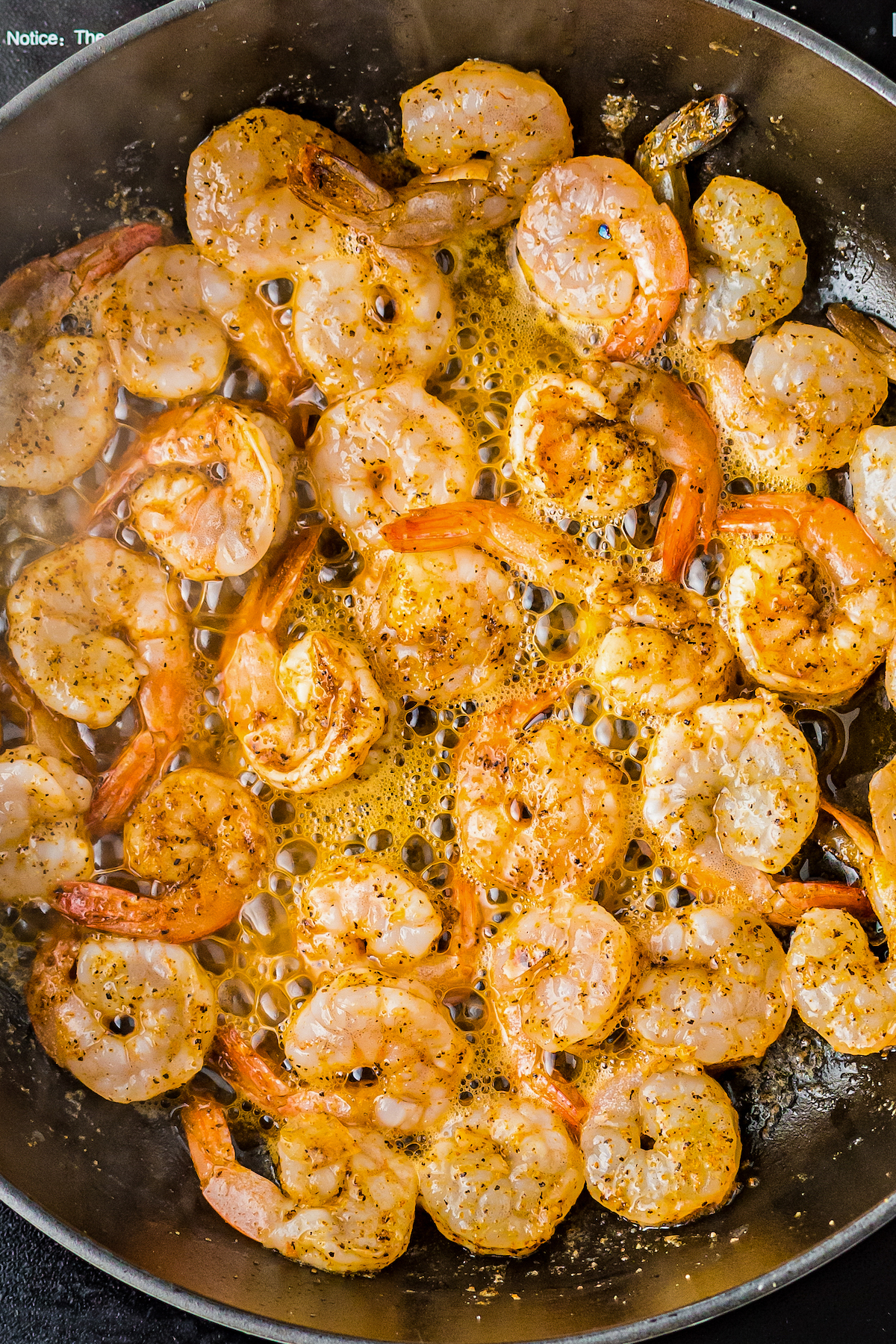 Seasoned shrimp cooking in a skillet.