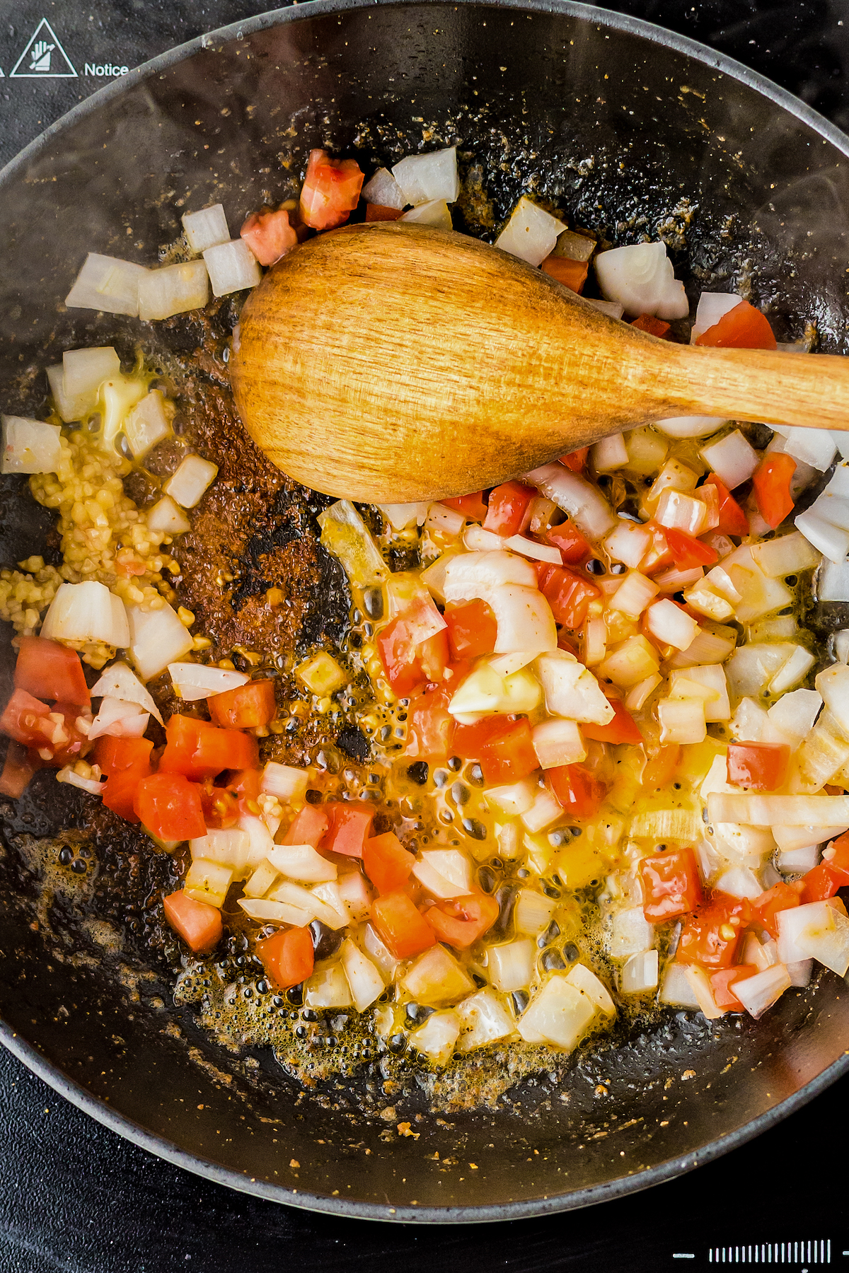 Onion, tomato, and garlic cooking in a skillet.