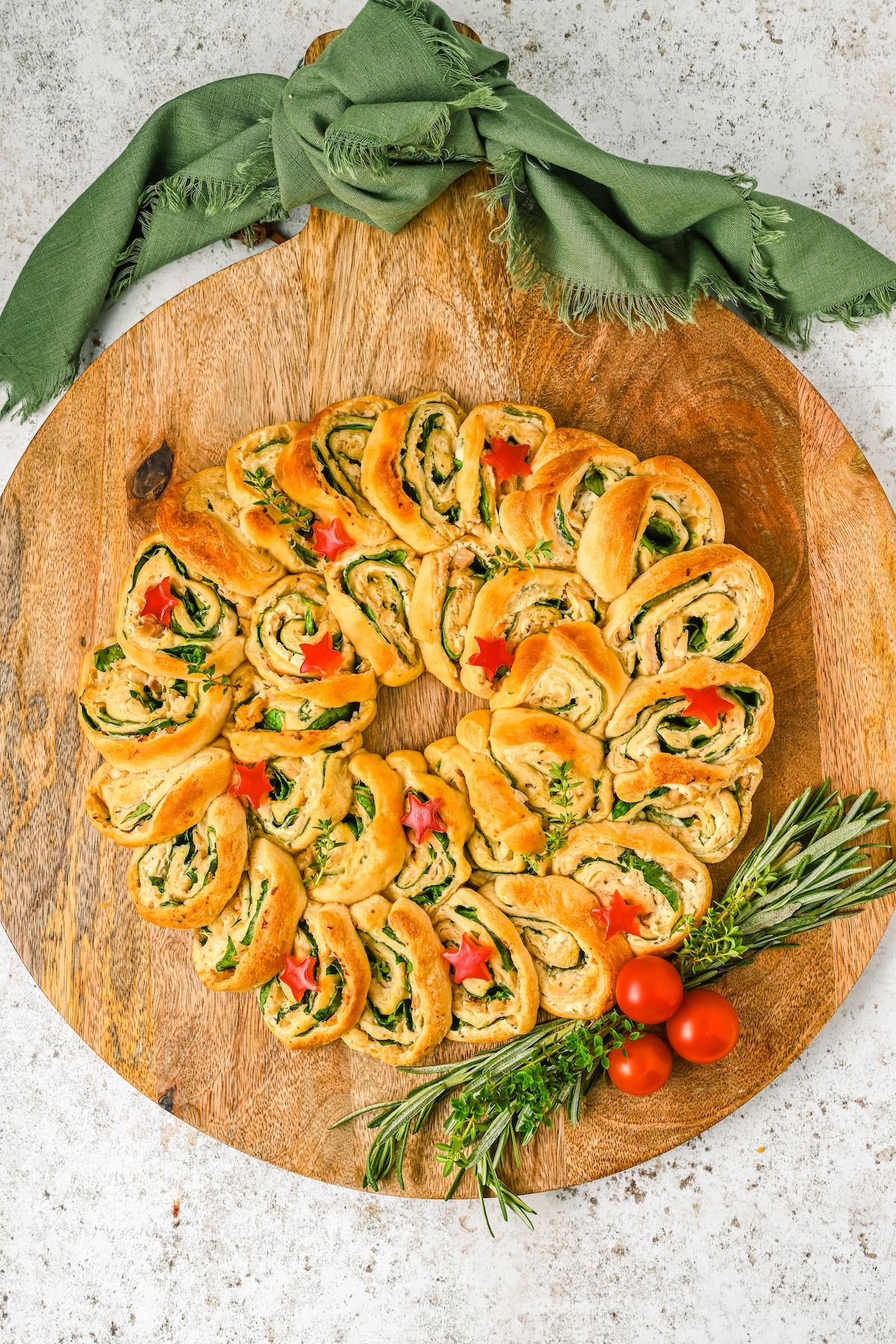 A crescent wreath garnished with tomatoes, rosemary, and stars cut out of bell pepper.