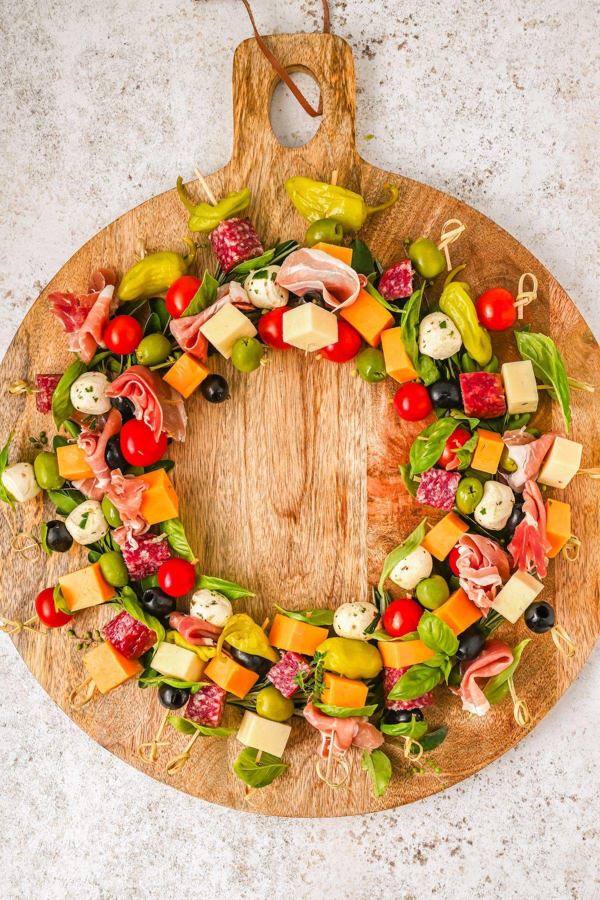 Skewers of appetizers arranged into a circle on a cutting board.
