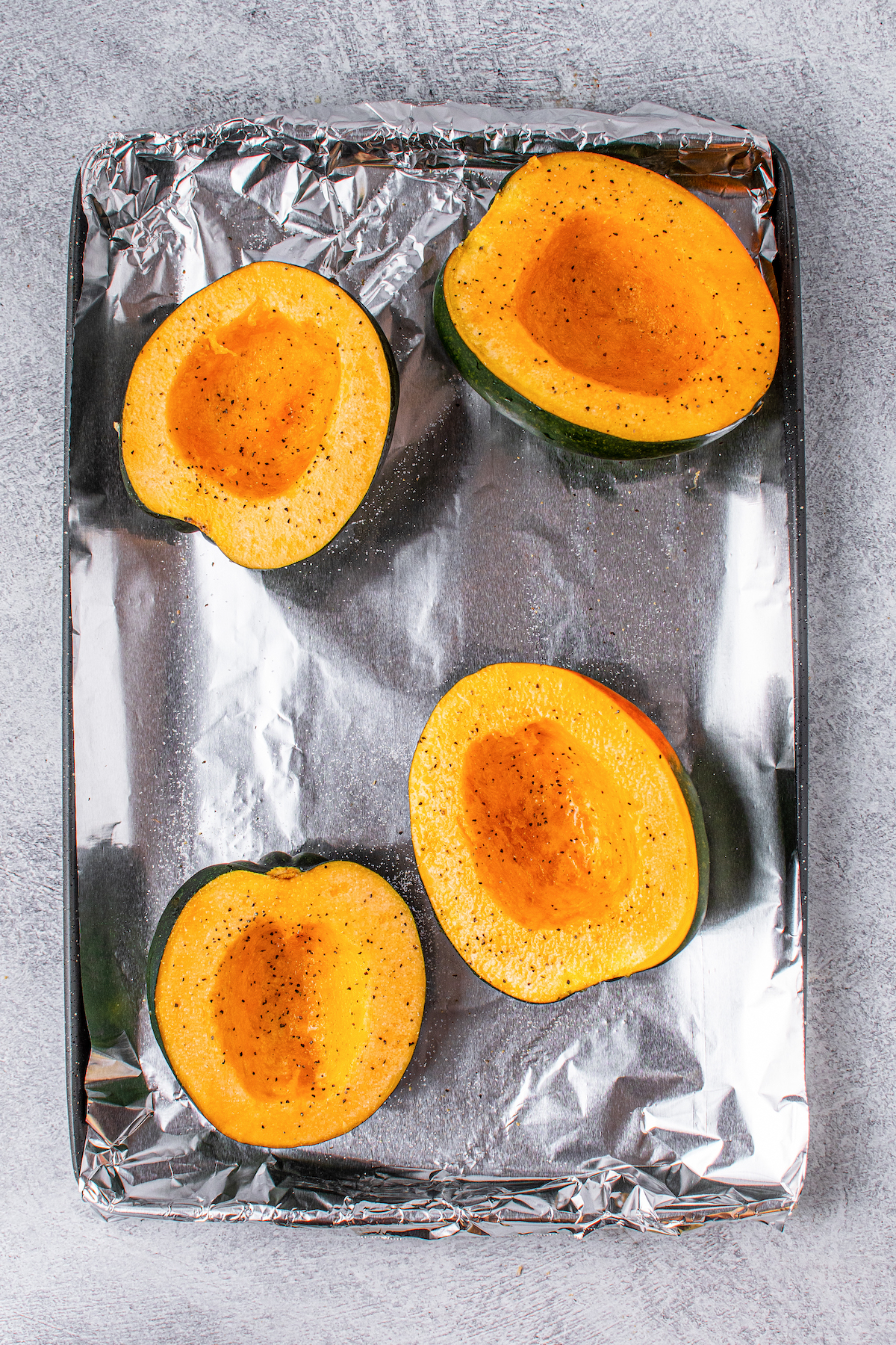 Halved and seeded acorn squashes in a baking tray.