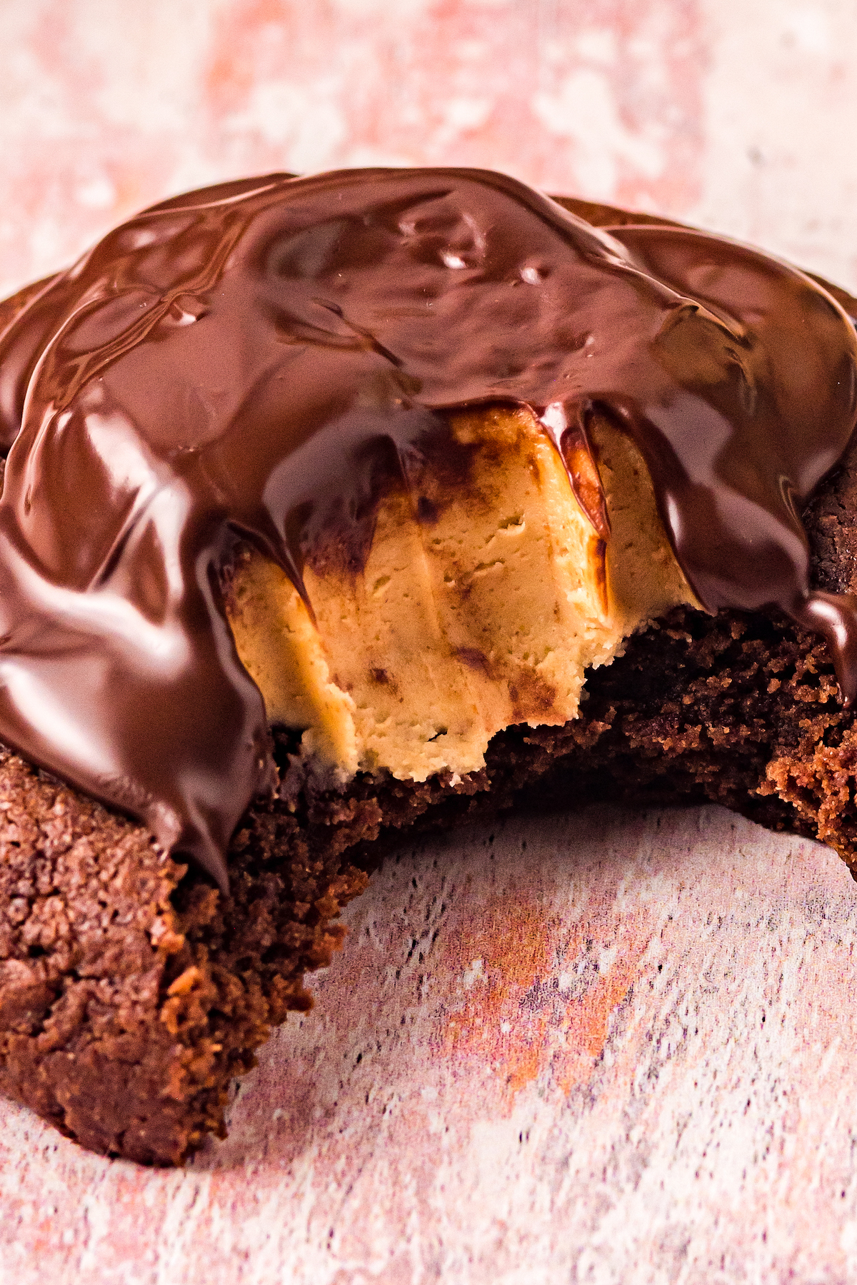 Glossy melted chocolate tops a peanut butter buckeye nestled in a chocolate cookie.