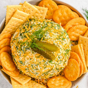 Overhead shot of a dill pickle and cheese spread appetizer with crackers.