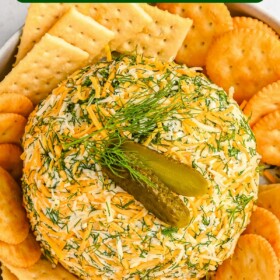 Pickle cheese ball on a tray with two kinds of crackers.
