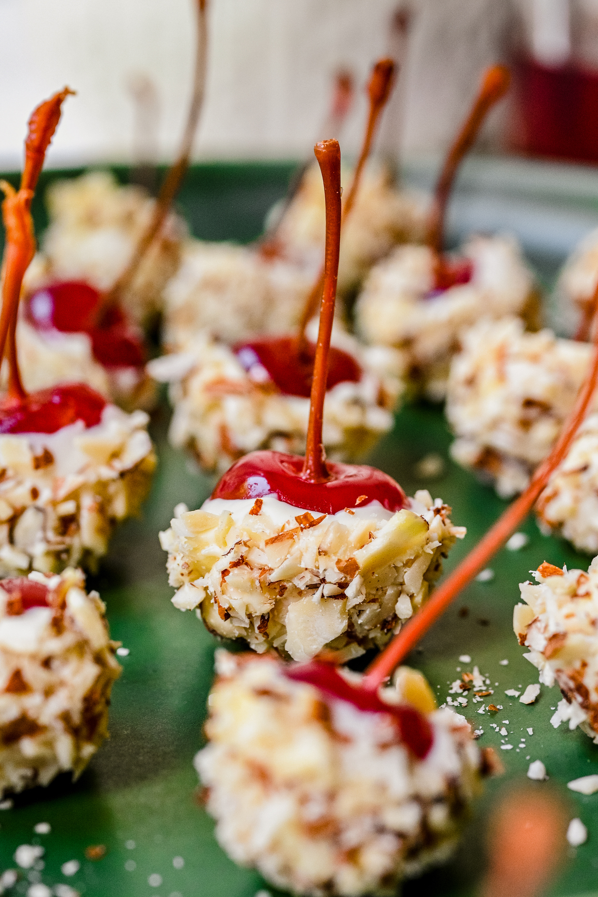 White-chocolate coated cherries lined up on a green serving plate.