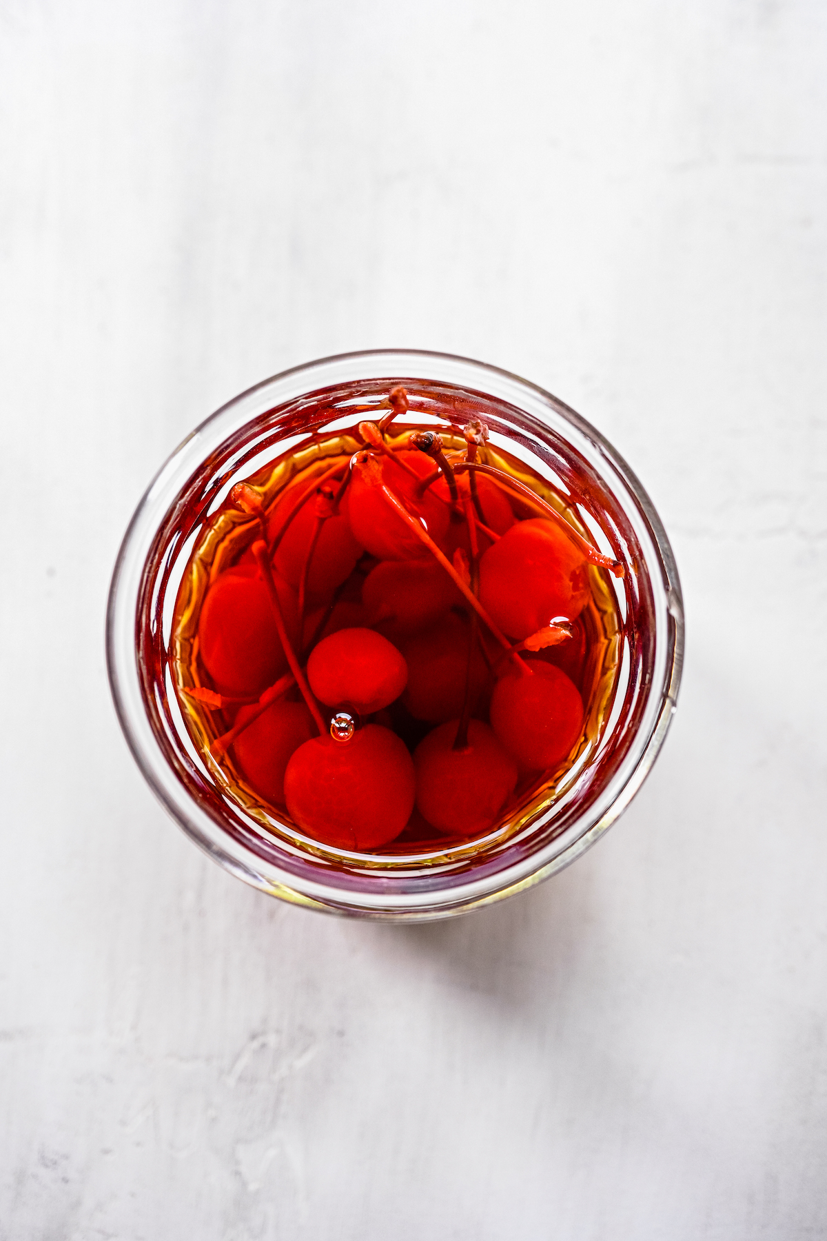 Overhead shot of a jar full of maraschino cherries, covered in liqueur.