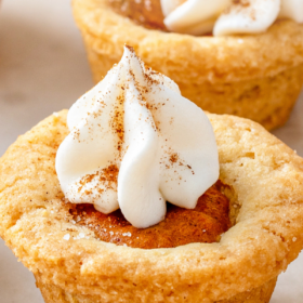 A pumpkin pie cookie with whip cream and cinnamon on top.