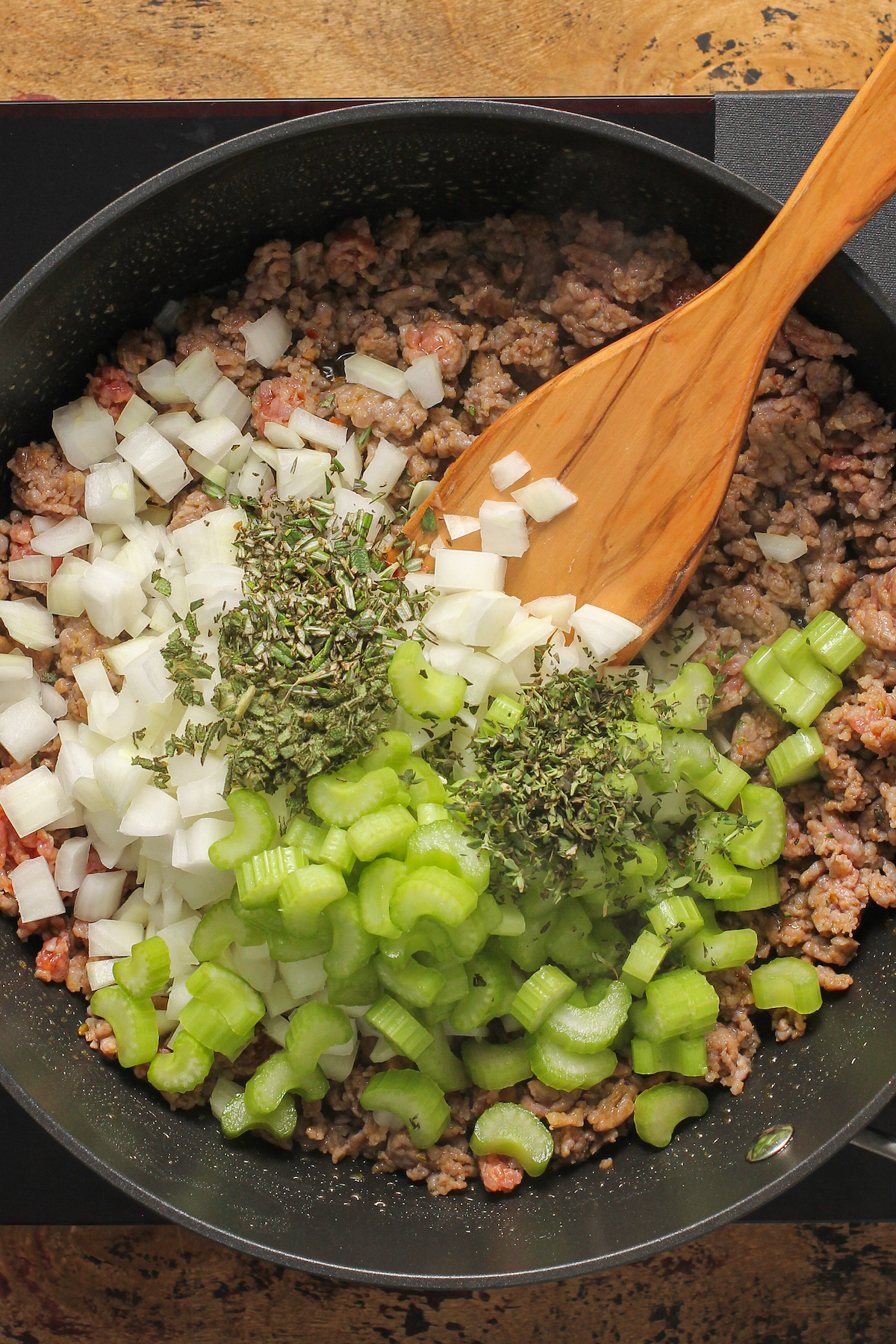 Sausage, onion, celery, herbs, and other ingredients in a skillet.
