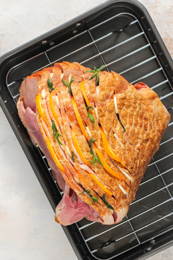 Showing how to cook a spiral ham with herbs and thin slices of orange tucked in between the slices of the ham.