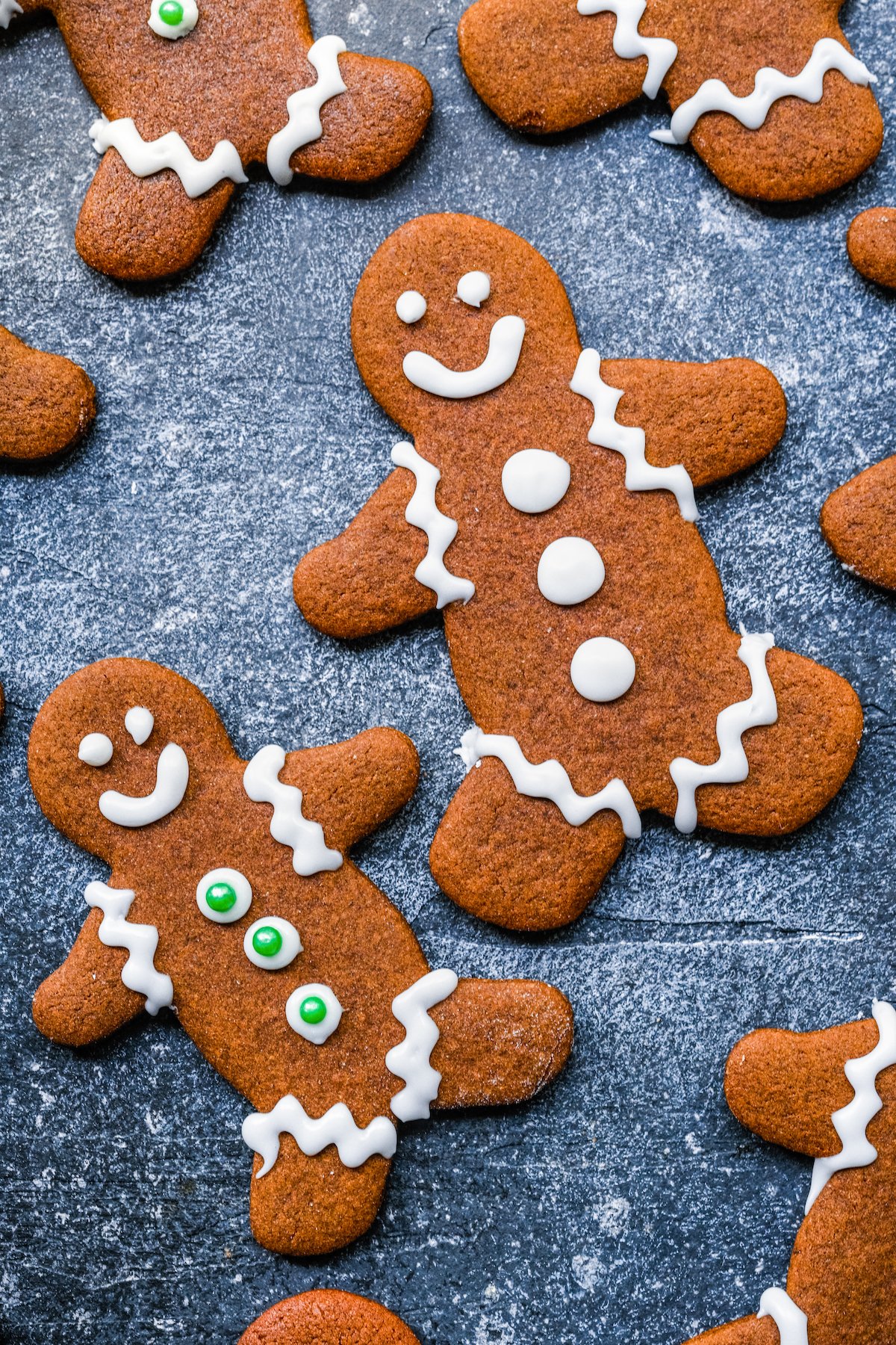 Gingerbread man cookies with royal icing faces, clothes, and buttons.