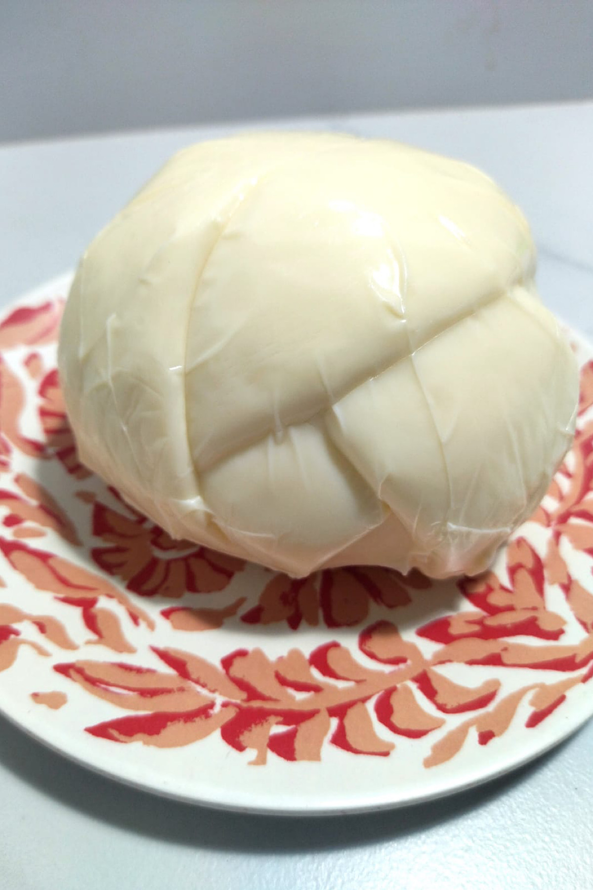 Close-up of whole oaxaca cheese on a plate.