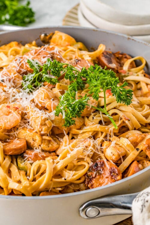 A large cooking pot of creamy pasta with shrimp, chicken, and sausage.