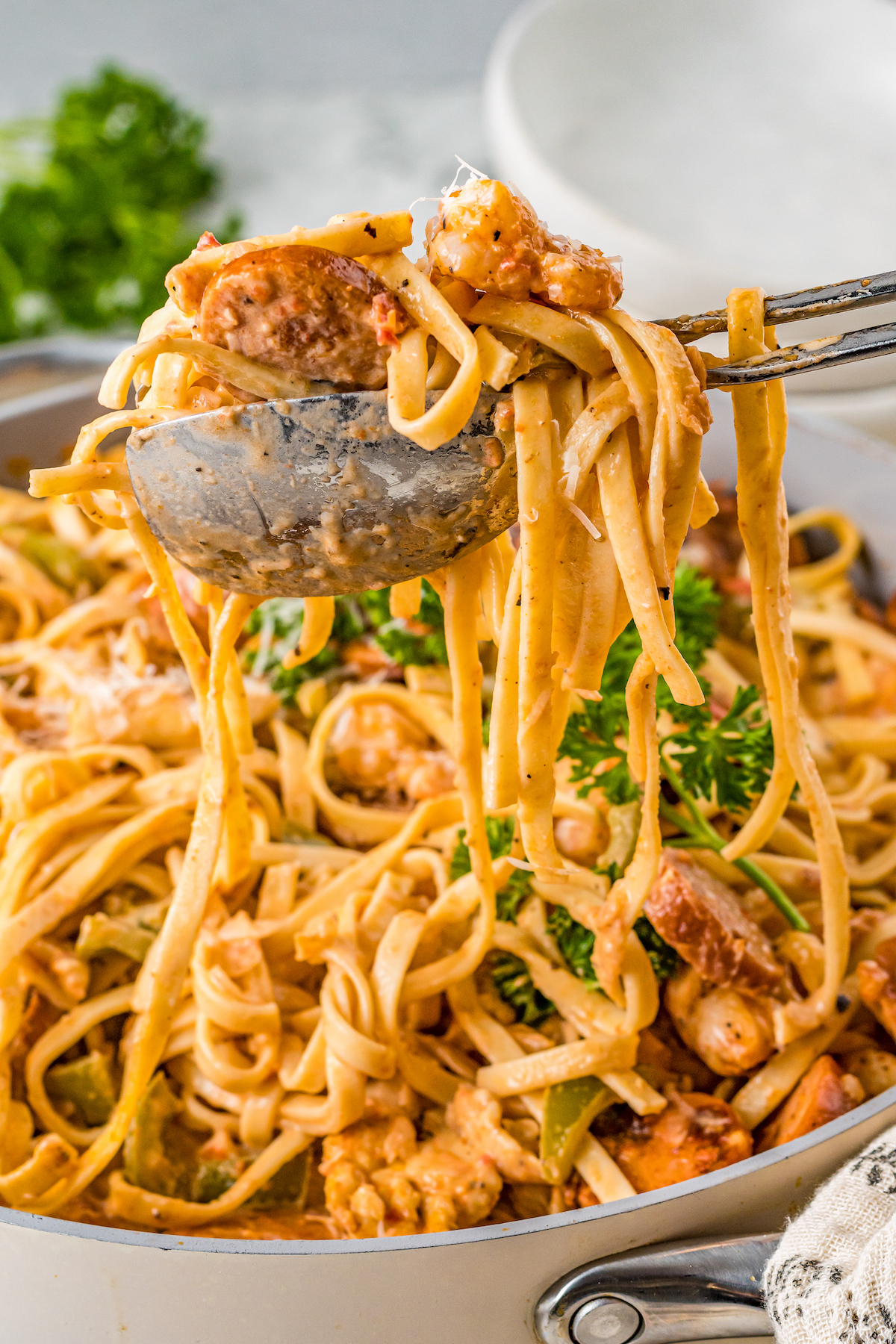 Featuring chicken, sausage, and shrimp, this creamy Cajun Pasta recipe is tossed in a creamy and spicy sauce with tender linguine pasta. Creamy Cajun pasta being served with serving utensils.