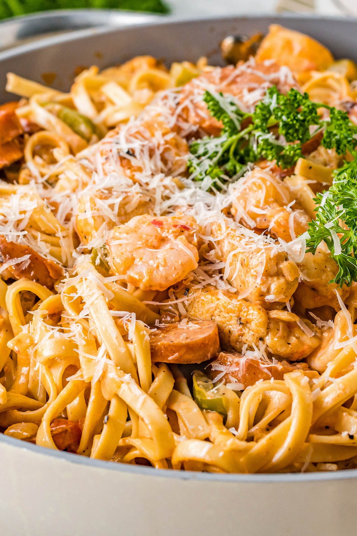 Close-up shot of loaded Cajun pasta, garnished with grated Parmesan and chopped parsley.