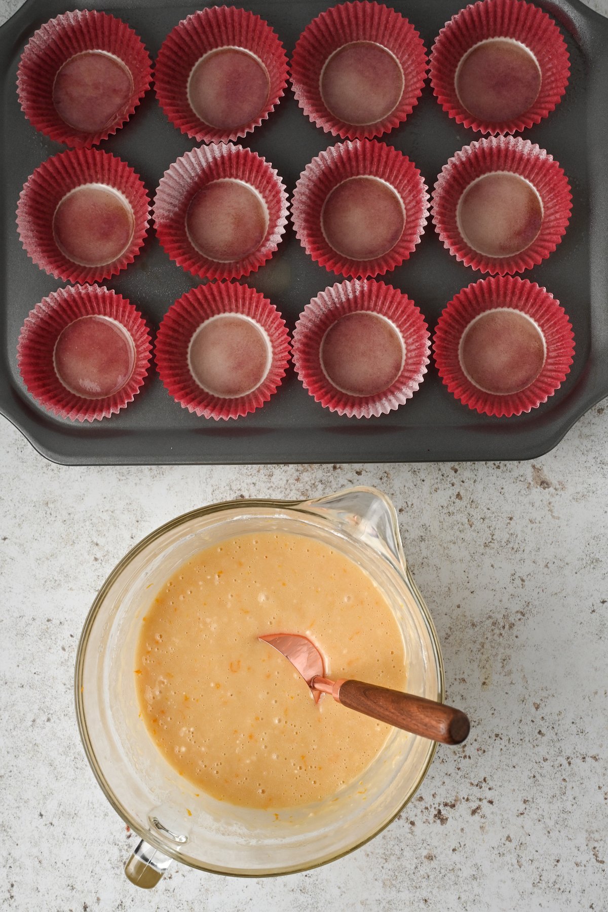 Mixed mantecada batter and a lined muffin tray.