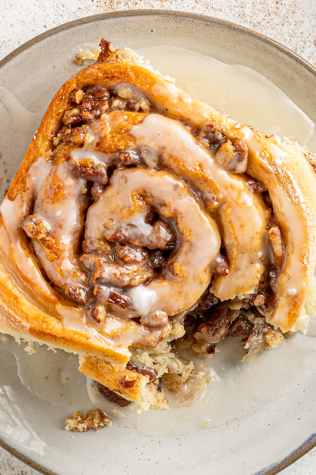 Overhead shot of an iced pecan cinnamon roll with a bite taken from it.