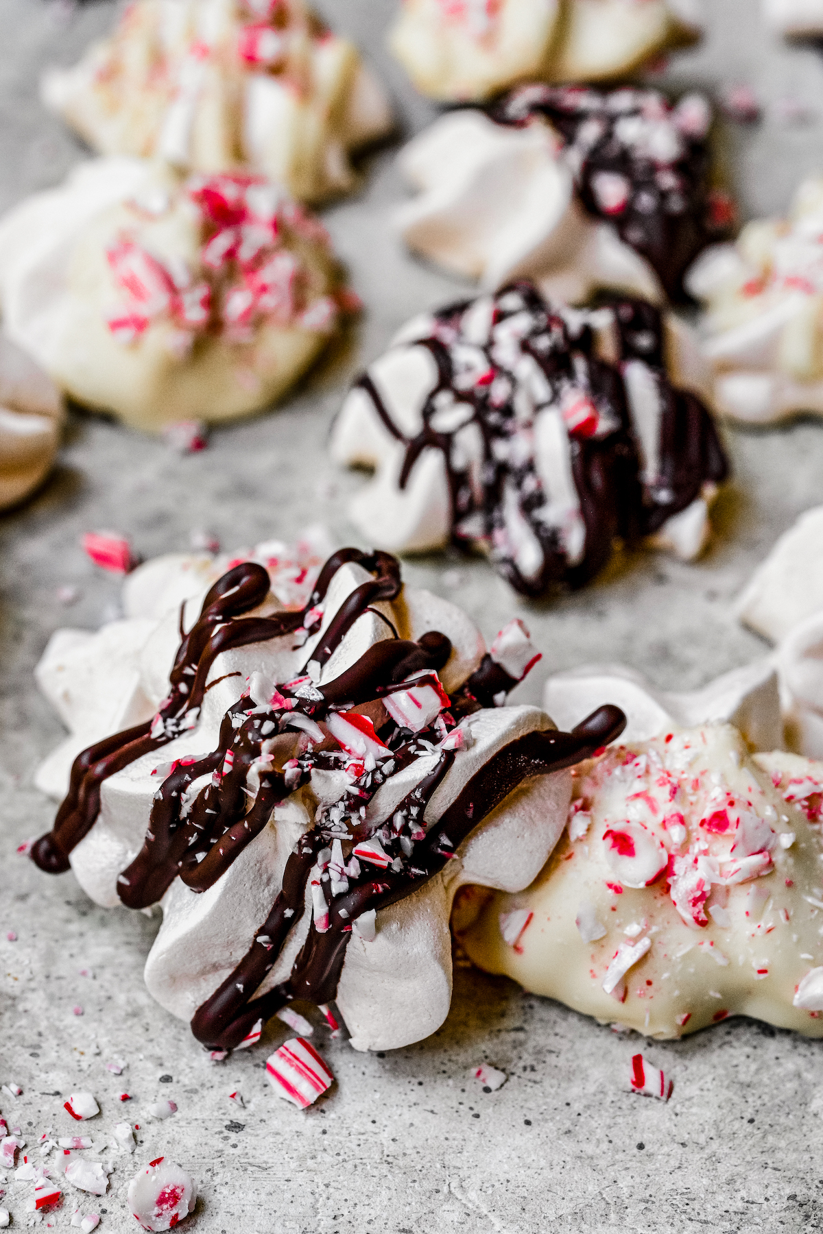 Christmas meringue cookies with chocolate drizzle and candy cane sprinkles.