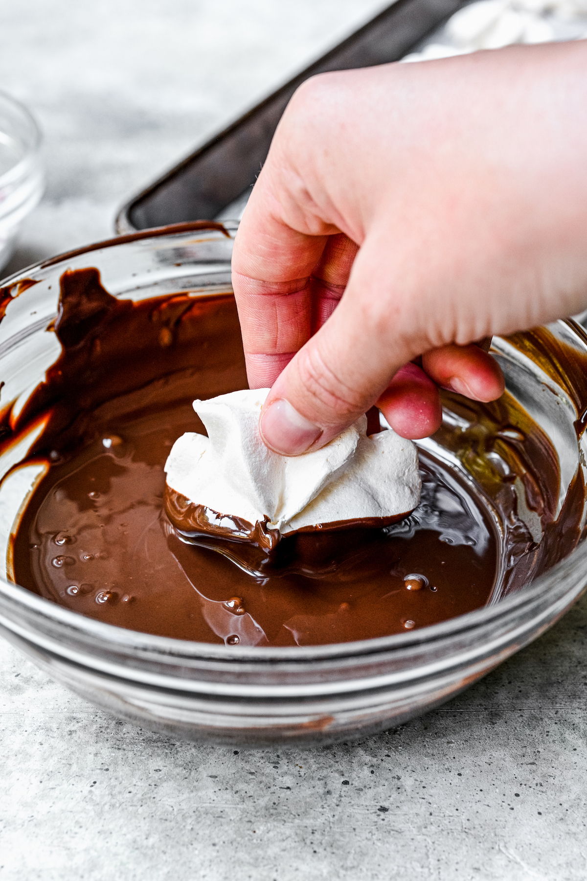 Dipping a cookie halfway into melted semisweet chocolate.