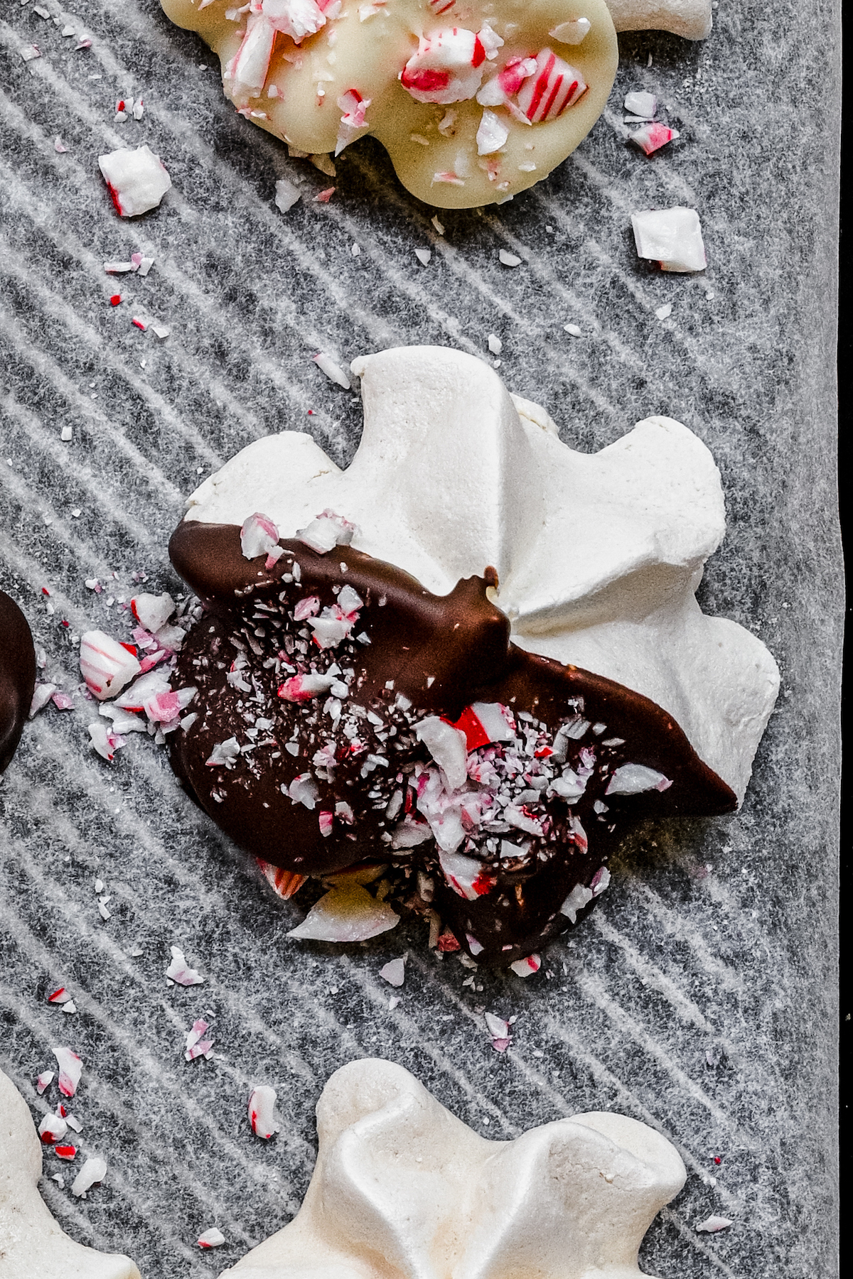 A chocolate-dipped meringue cookie decorated with crushed candy canes.