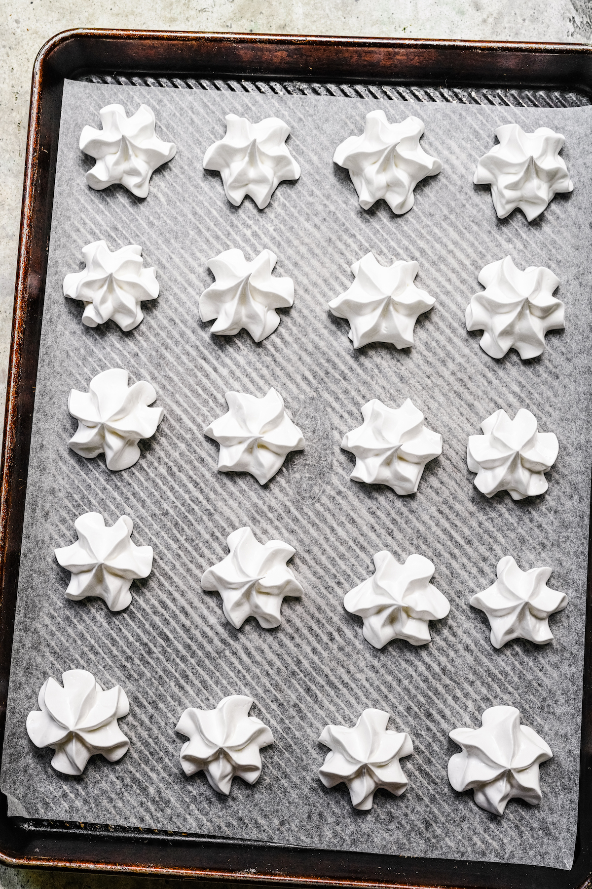 Piped meringues on a parchment-lined baking sheet.