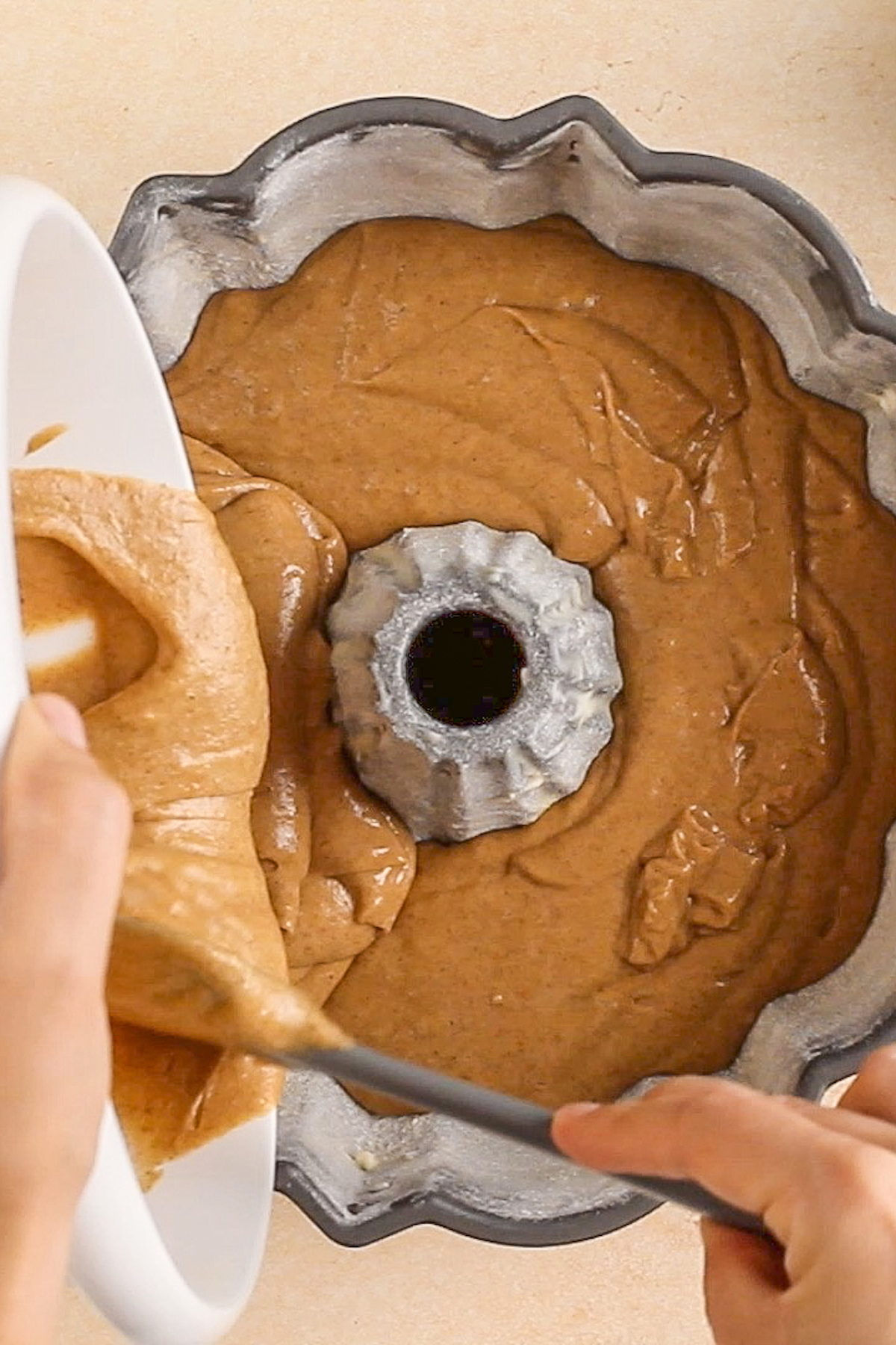 Cake batter being poured into a Bundt pan.