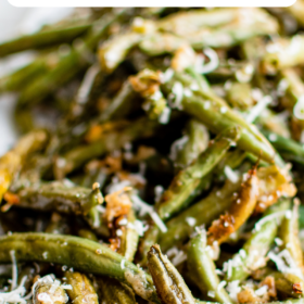 Roasted green beans on a plate with parmesan cheese on top.