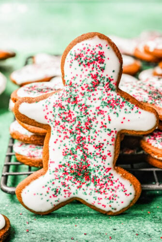 A gingerbread cookie dipped in icing and sprinkled with red and green sprinkles.