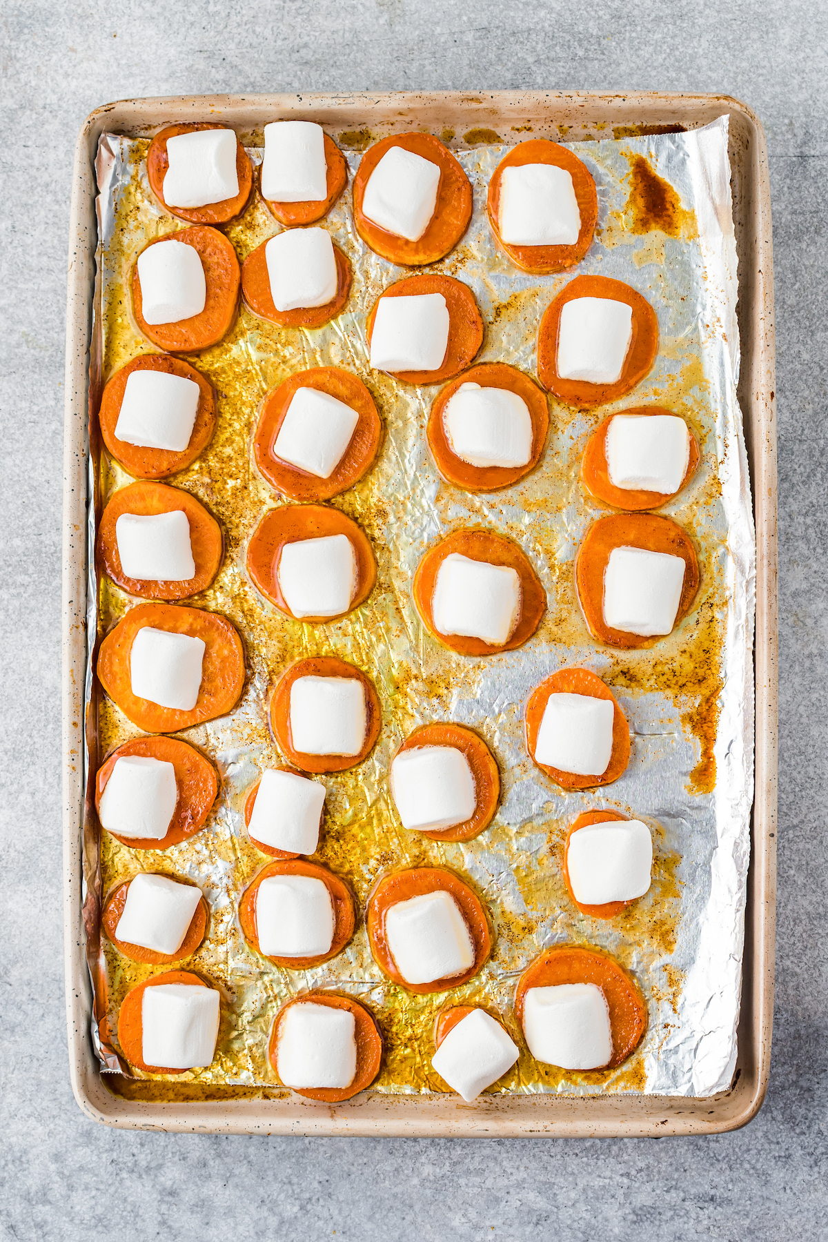 Baked sweet potato bites with marshmallows on top, before melting.