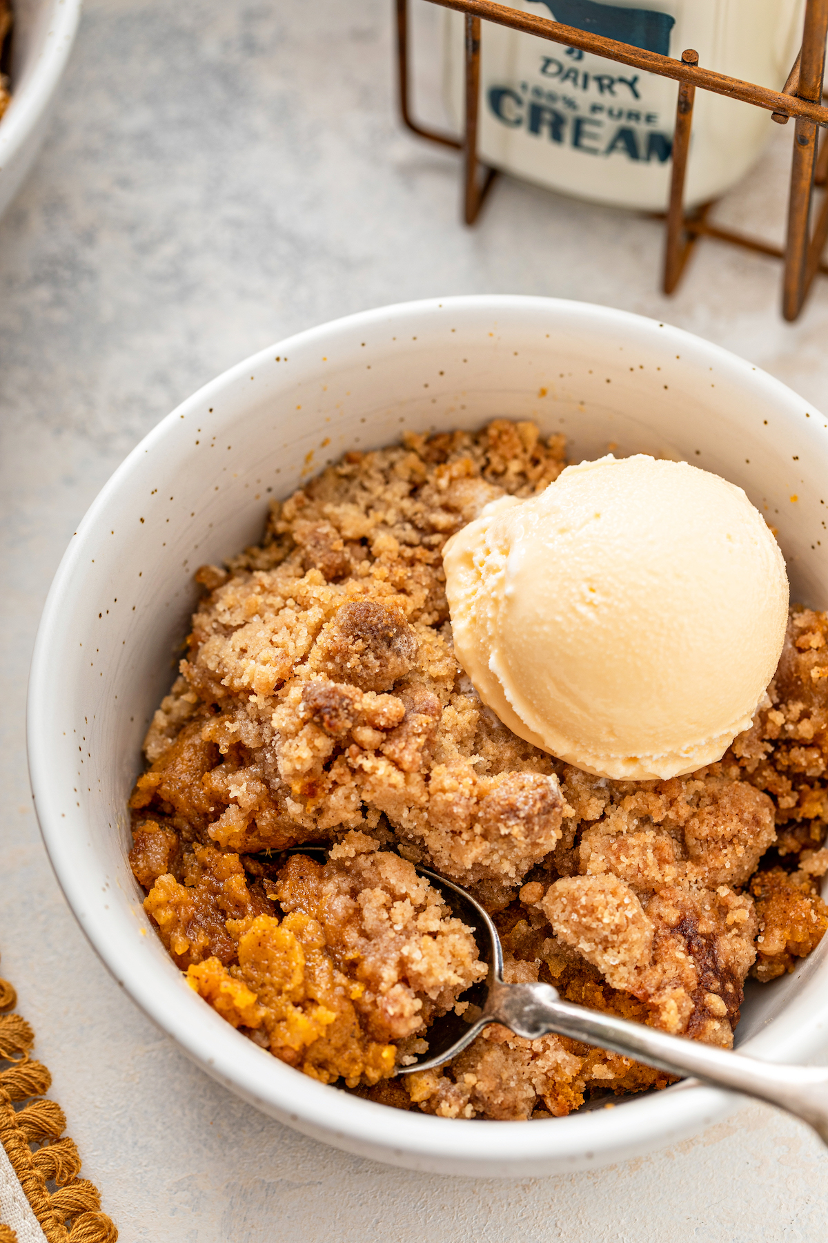 A spoon taking a bite out of a bowl of sweet potato crumble.