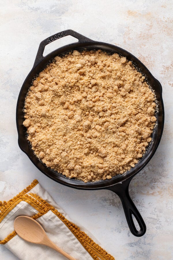 Crumb topping spread on top of sweet potato filling in a cast iron skillet.