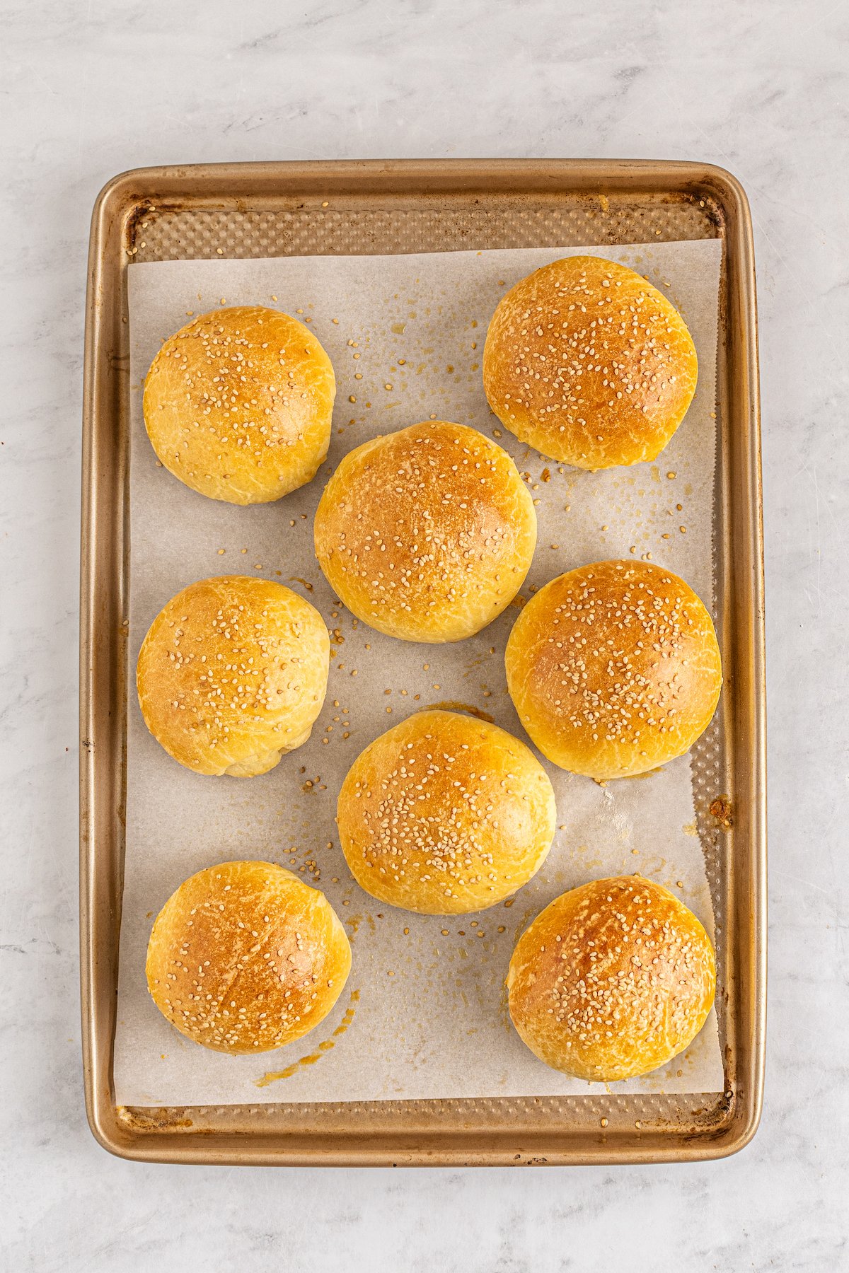 Baked brioche buns on a baking sheet.