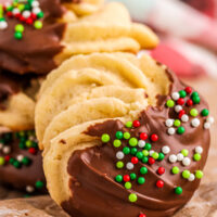 A danish butter cookie dipped in chocolate with Christmas sprinkles on parchment paper.