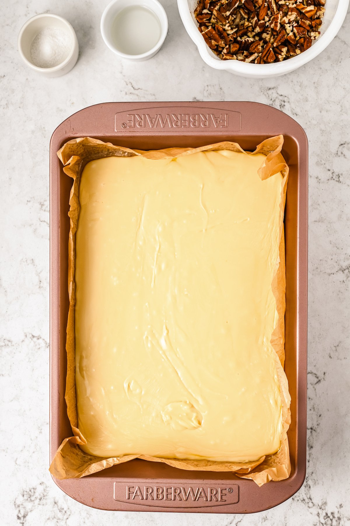 A white chocolate candy mixture poured into a parchment-lined pan.