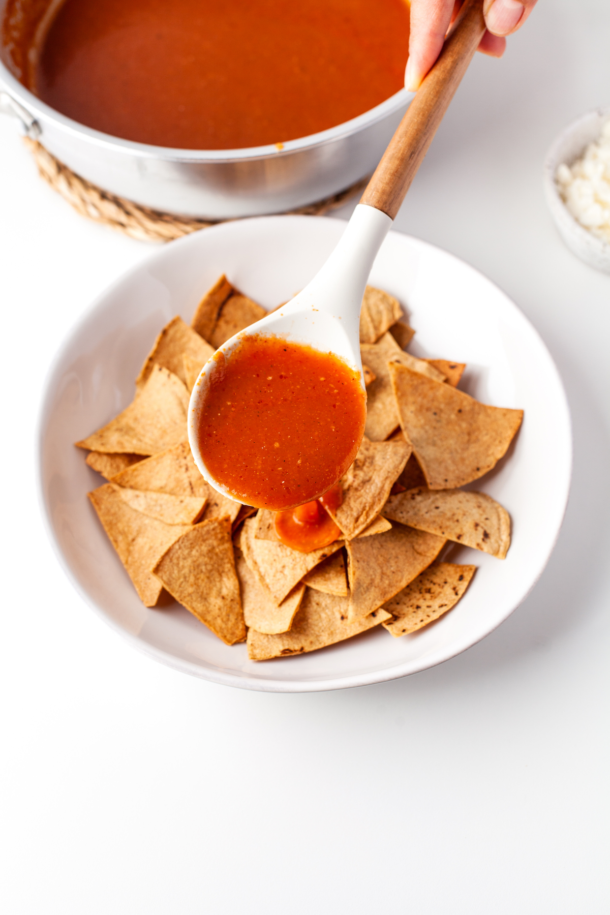 Pouring salsa over the tortilla chips. 