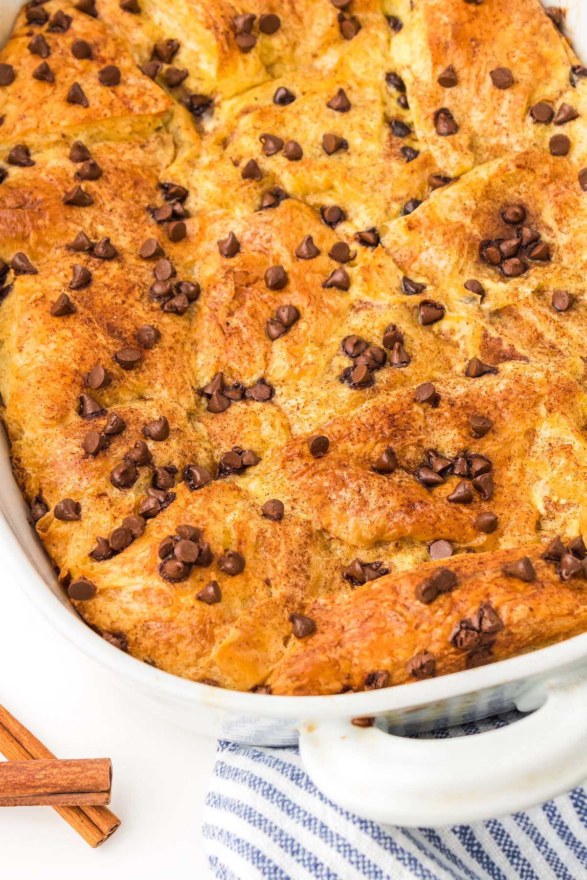 Close-up of chocolate chip croissant French toast bake in a white baking dish.