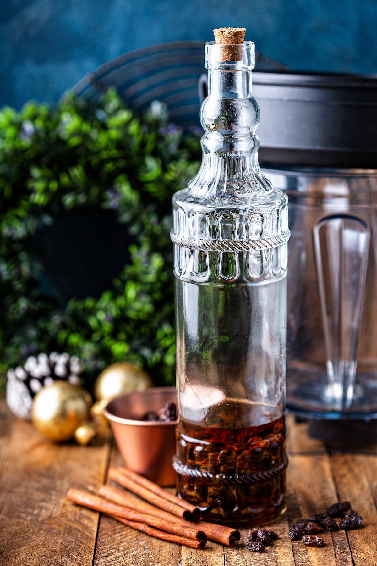 Rum, raisins and cinnamon sticks in a glass bottle with a stopper on top.