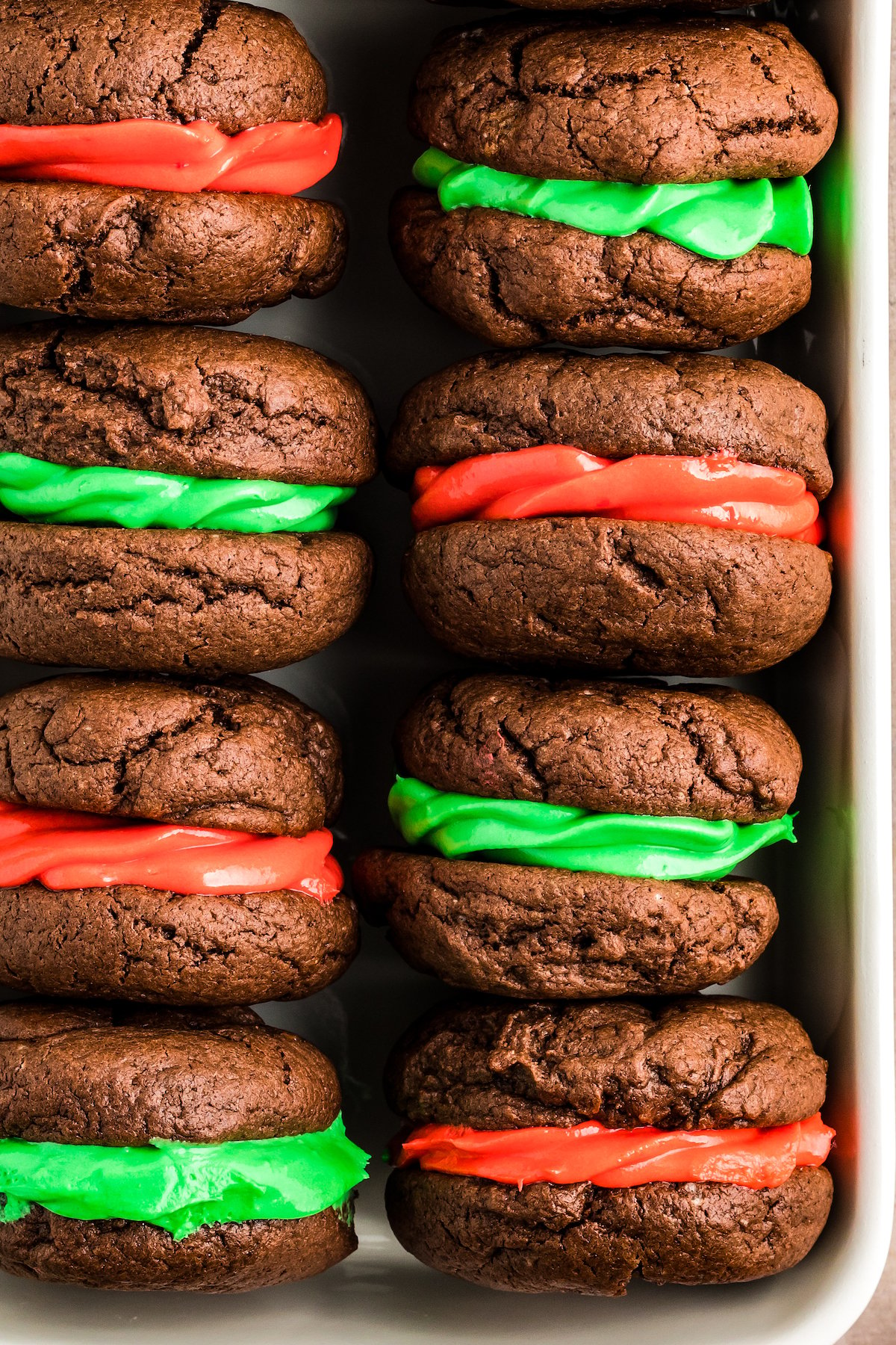 Chocolate whoopie pies sandwiched together with red frosting and green frosting.