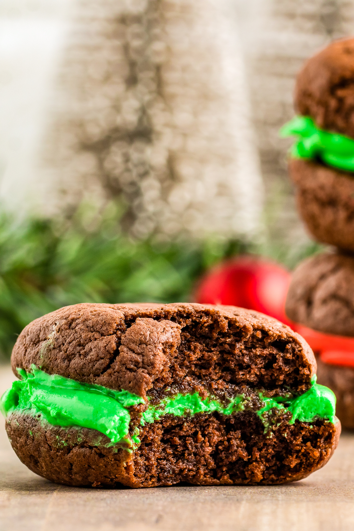 A soft, chocolate sandwich cookie with green marshmallow filling. One bite has been taken from the cookie.
