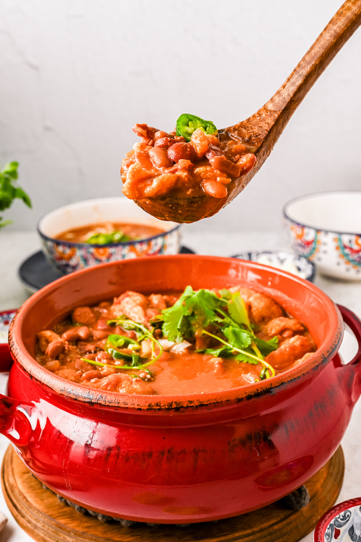 Frijoles charros on a spoon with diced onion and cilantro.