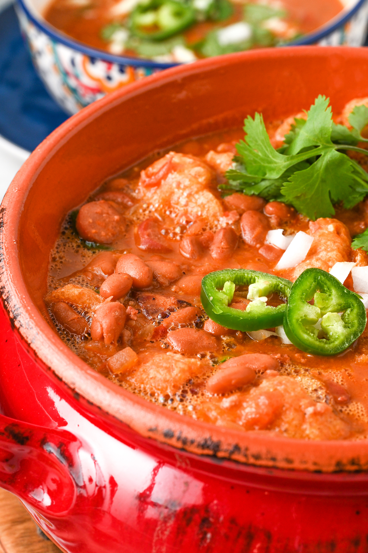 Close-up of frijoles charros with onion, jalapeño, and cilantro on top. 