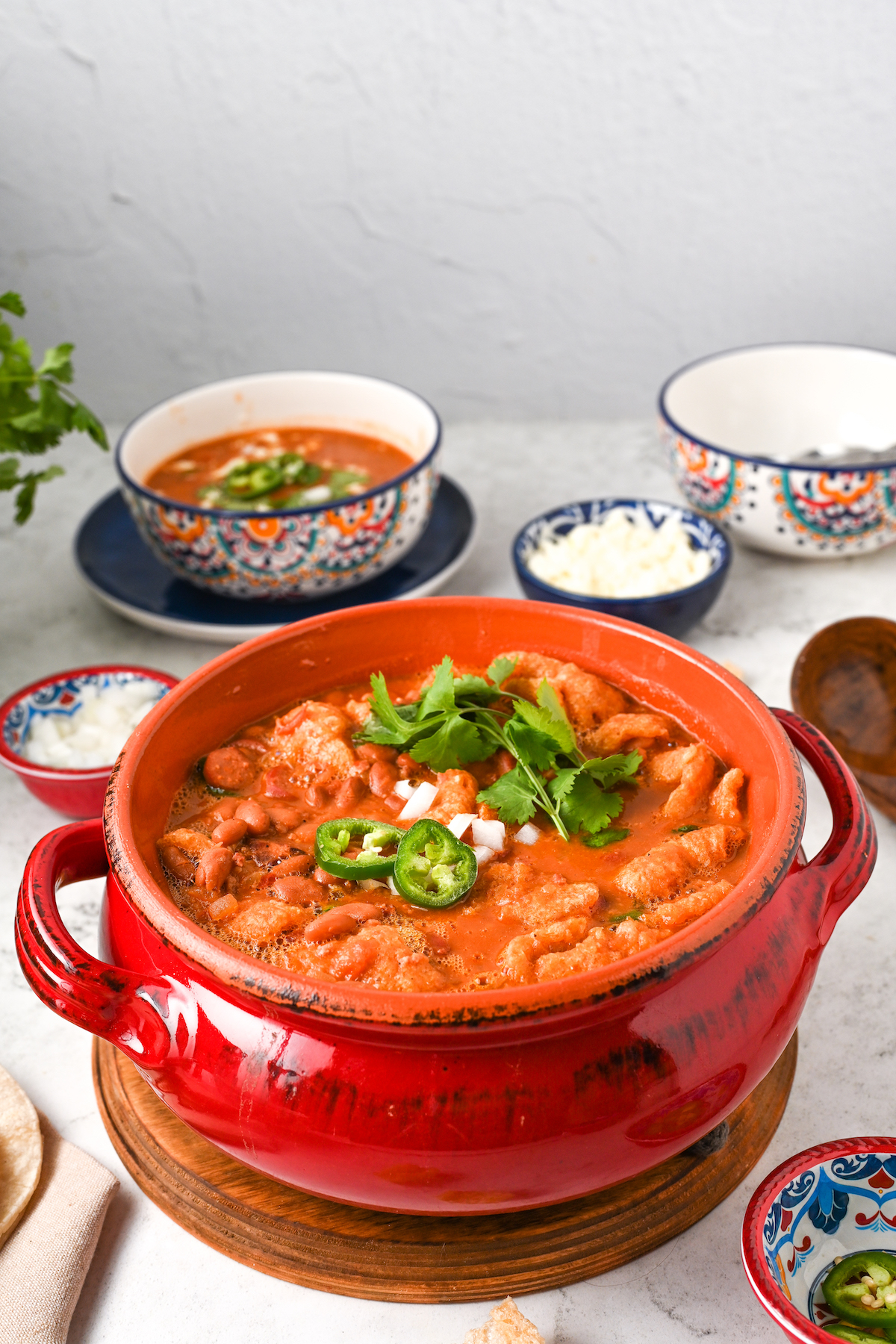 Frijoles charros topped with diced onion, jalapeño, and cilantro in a clay pot. 