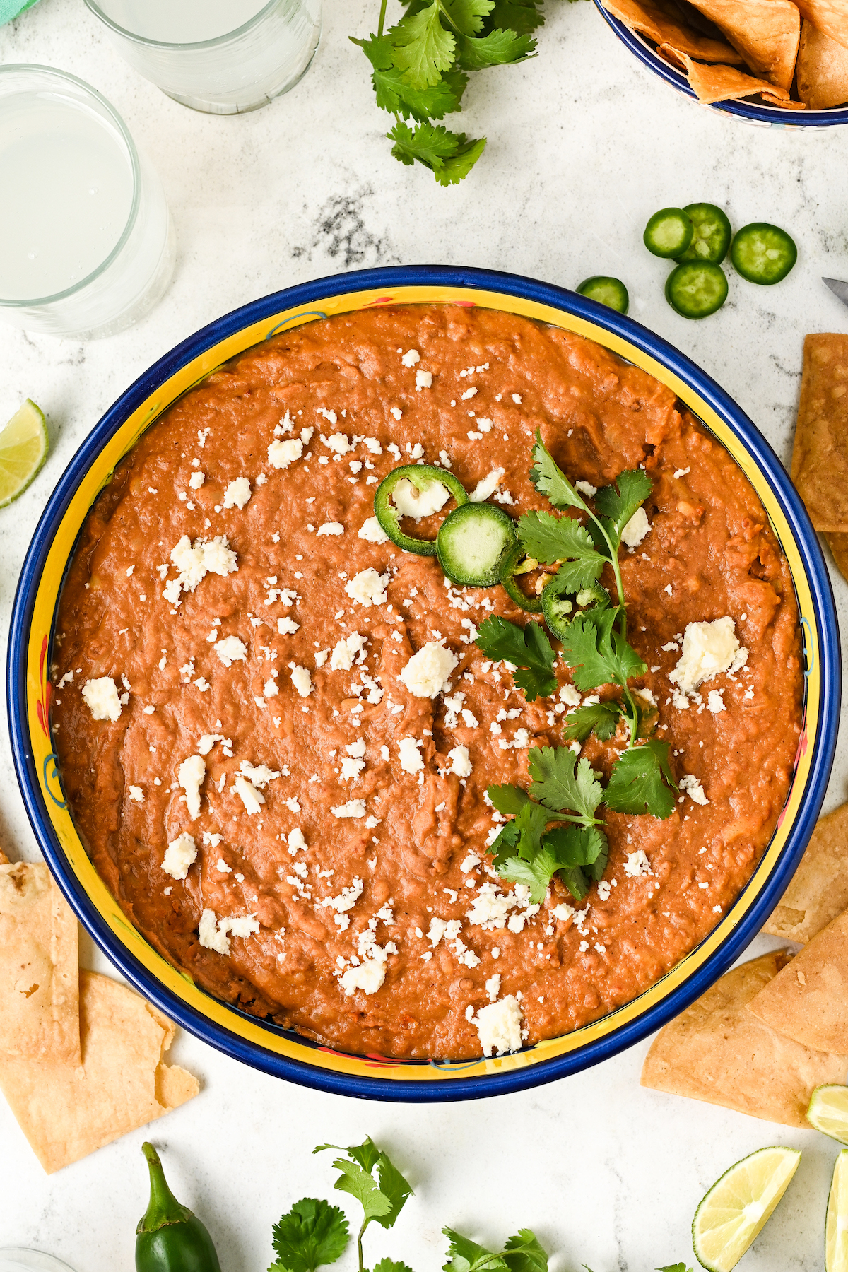 Frijoles puercos topped with crumbled queso fresco, sliced jalapeño, and cilantro.