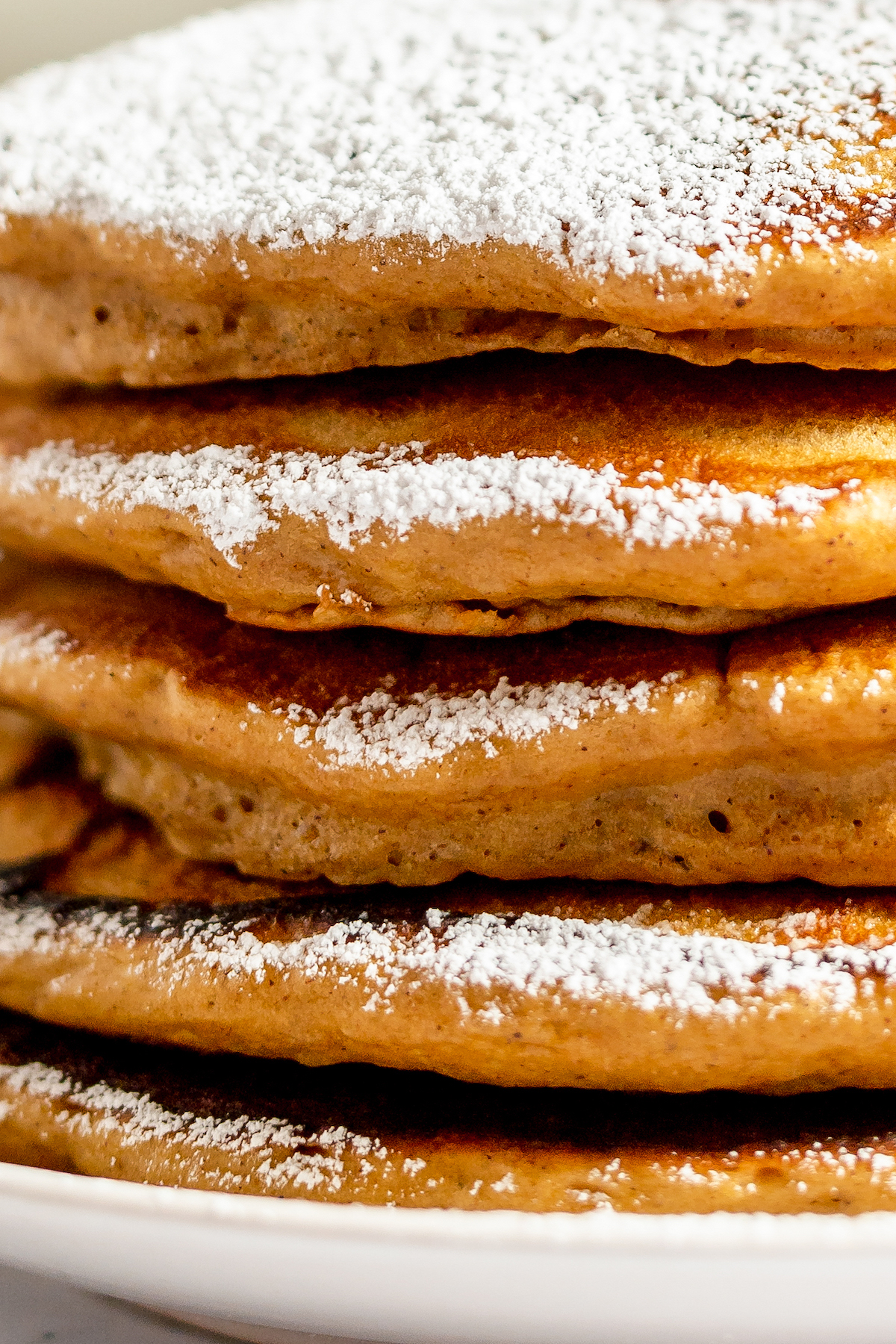 Close-up shot of pancake edges. Each cake has been dusted with powdered sugar.