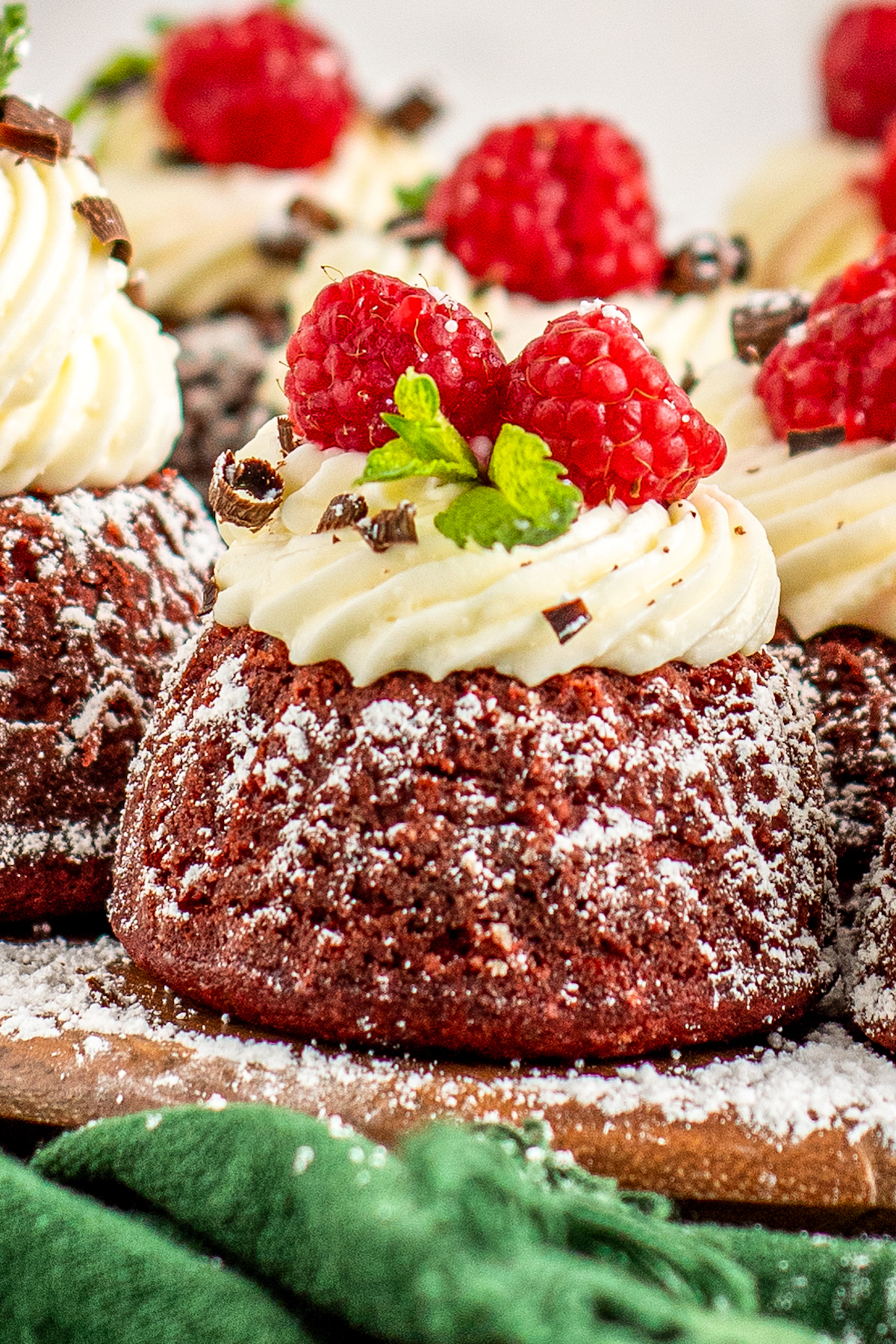 Close-up of mini red velvet bundt cake with cream cheese frosting and a raspberry on top. 