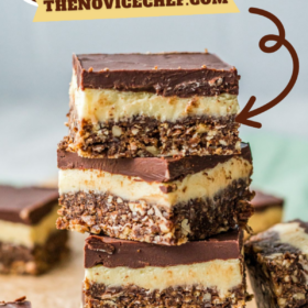No bake nanaimo bars stacked on top of each other on parchment paper.
