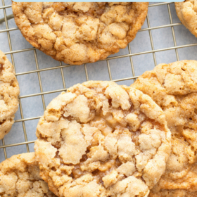 Cookies stacked on top of each other on a cooling rack on top of parchment paper.