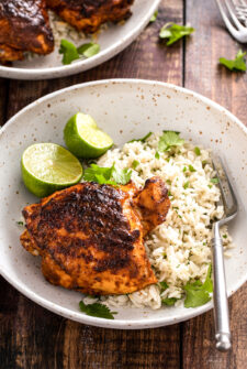 Pollo asado served with rice, cilantro, and lime wedges.
